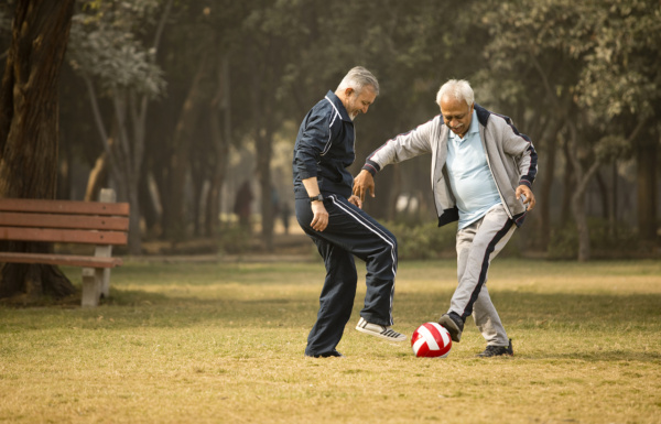 Two old men having fun playing with ball on green grassy lawn